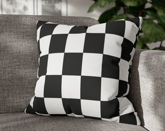 May include: Black and white checkered throw pillow with a square pattern. The pillow is sitting on a gray couch.