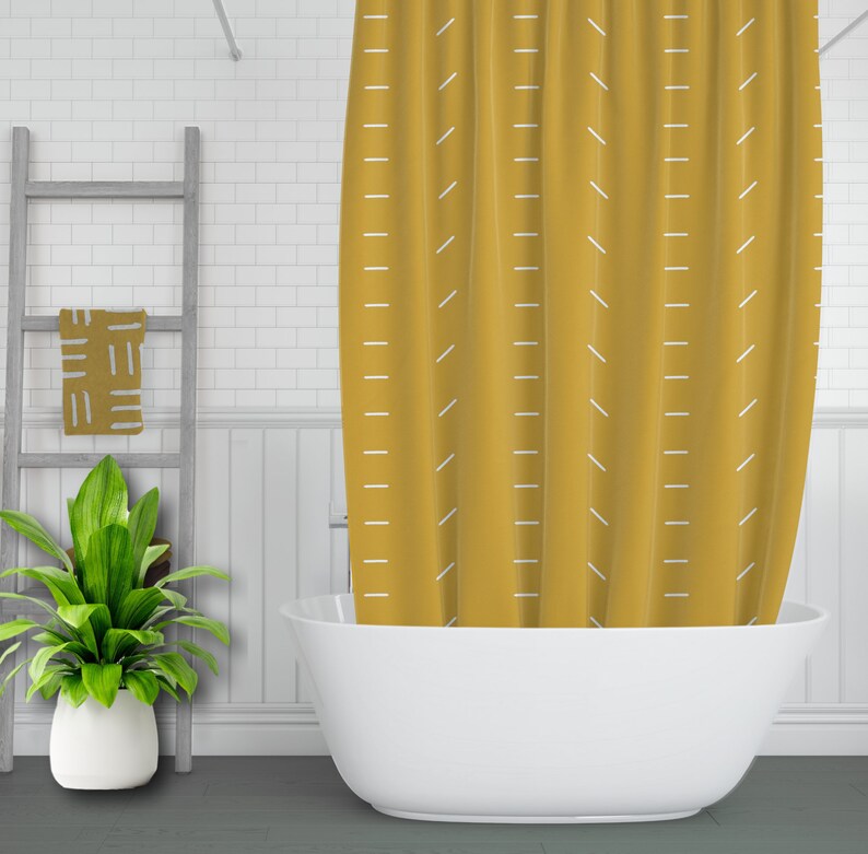 May include: A yellow shower curtain with a white geometric pattern. The curtain is hanging in a bathroom with a white bathtub.