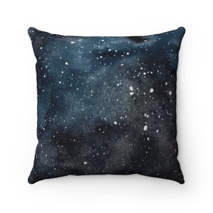 May include: A dark blue throw pillow with a white watercolor galaxy print. The pillow is soft and comfortable, perfect for adding a touch of space to your home decor.