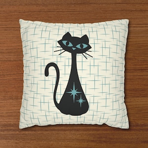 May include: A white pillow with a blue and white grid pattern. A black cat with blue eyes and stars is in the center of the pillow.
