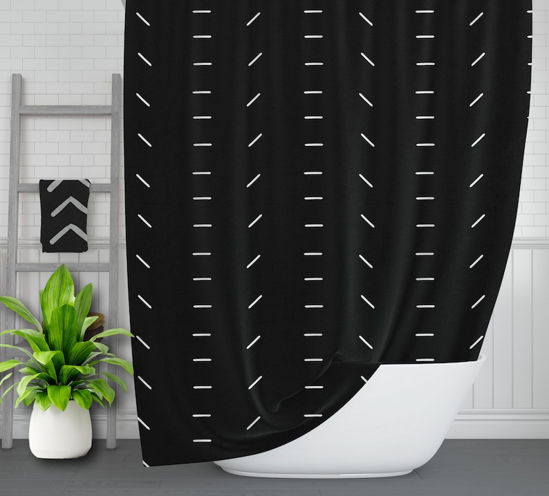 May include: Black shower curtain with a white geometric pattern of diagonal lines. The curtain is hanging in a bathroom with a white bathtub.