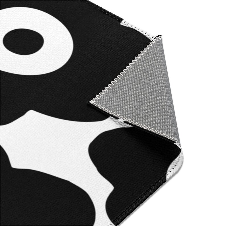 Peut inclure: Tapis &agrave; motifs noirs et blancs avec un dos noir. Le tapis a un design g&eacute;om&eacute;trique avec de grands cercles et de petits cercles &agrave; l'int&eacute;rieur.