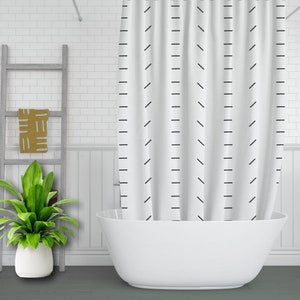 May include: White shower curtain with a black geometric pattern of diagonal and vertical lines. The curtain is hanging in a bathroom with a white bathtub.