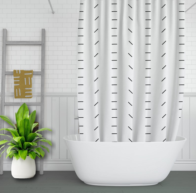 May include: White shower curtain with a black geometric pattern of diagonal and vertical lines. The curtain is hanging in a bathroom with a white bathtub.