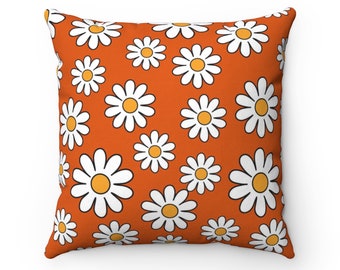May include: Orange throw pillow with a white daisy pattern.