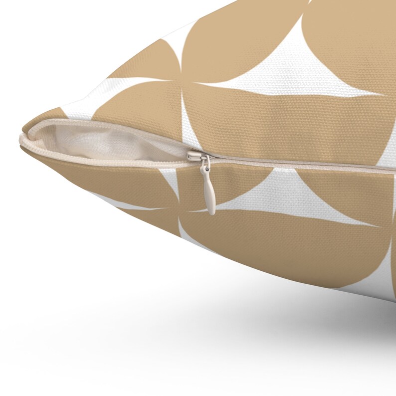 May include: Close-up of a decorative pillow with a geometric pattern. The pillow features a repeating design of tan circles against a white background. A silver zipper is visible along the edge. The pillow is designed for home decor.
