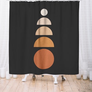 May include: Black shower curtain with a minimalist geometric design. The design features a series of stacked shapes in shades of white, beige, and orange, creating a modern and abstract pattern. The curtain is hanging in front of a white bathtub.