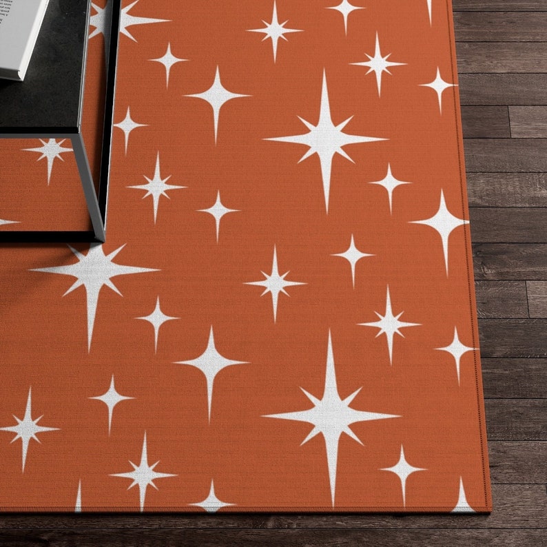May include: A rust-colored rug with a repeating pattern of white starbursts.