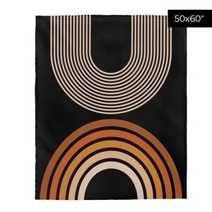 May include: A black throw blanket with a geometric design featuring a large, beige, striped arch shape at the top and a smaller, multi-colored arch shape at the bottom. The blanket is 50 inches by 60 inches.