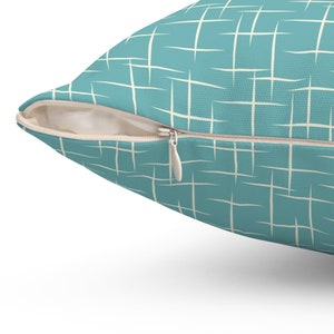 May include: A teal blue throw pillow with a white geometric pattern. The pillow has a zipper closure.