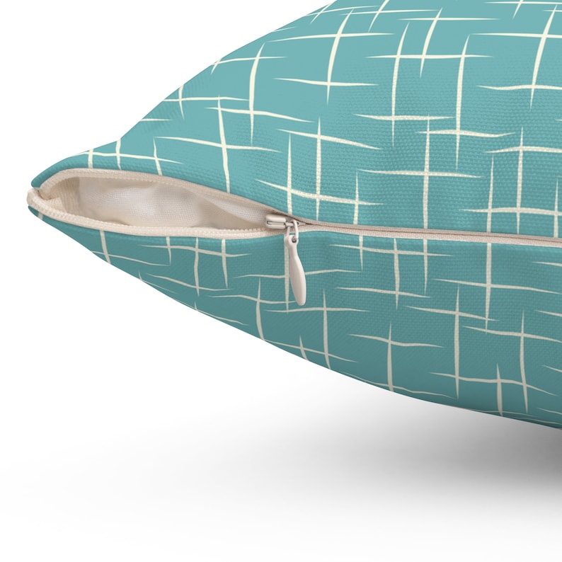 May include: A teal blue throw pillow with a white geometric pattern. The pillow has a zipper closure.