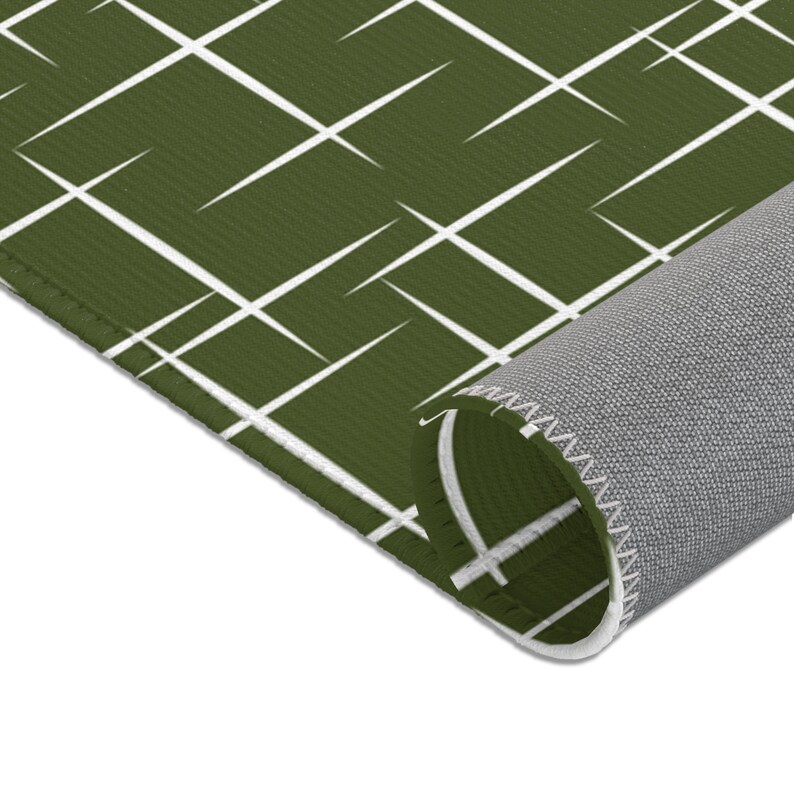 May include: A green and white geometric patterned rug with a white border. The rug is rolled up, showing the gray backing.