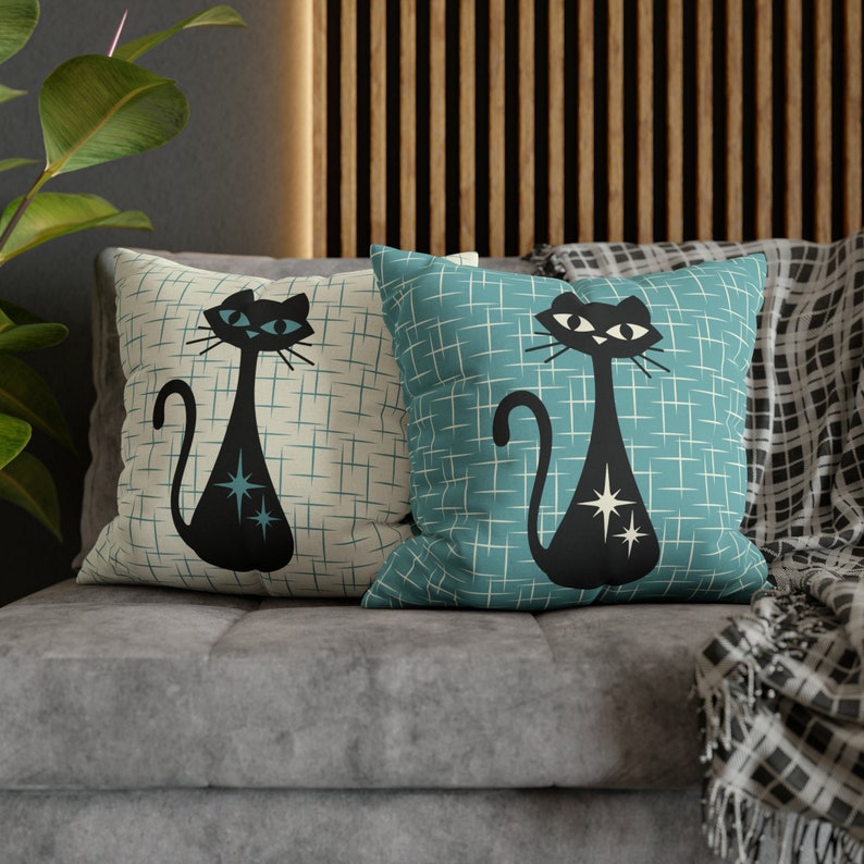 May include: Two decorative throw pillows with a retro design featuring black silhouettes of cats with blue eyes and white stars on a light blue and white checkered background.