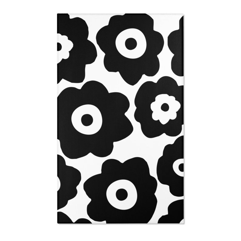 Peut inclure: Tapis &agrave; motifs floraux noir et blanc avec de grandes fleurs stylis&eacute;es. Les fleurs ont un design simple et circulaire avec un centre blanc.