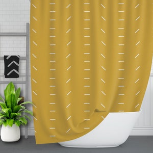 May include: A mustard yellow shower curtain with a white geometric pattern. The curtain is hanging in a bathroom and is partially covering a white bathtub.