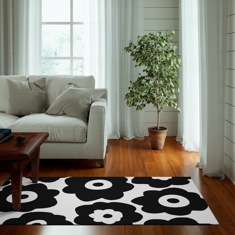 Peut inclure: Tapis de salon noir et blanc avec un motif de grandes fleurs. Le tapis est pos&eacute; sur un sol en bois dans un salon.