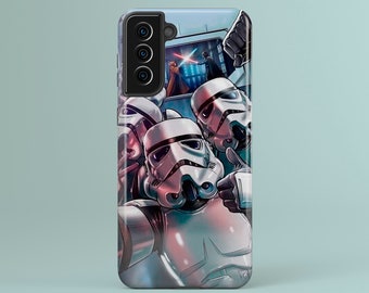 May include: A phone case featuring a Star Wars-themed design. The case depicts Stormtroopers taking a selfie, with a scene of Darth Vader and a Jedi in the background. The case is white, gray, and blue.