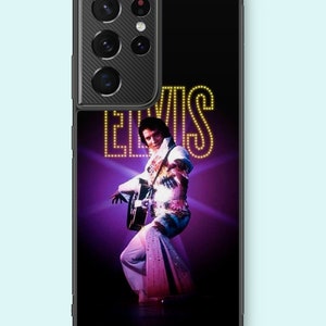 May include: Black phone case featuring a vibrant image of Elvis Presley playing a guitar on stage. The image includes the word "ELVIS" in yellow illuminated letters against a purple background. The phone case is designed to fit a smartphone.