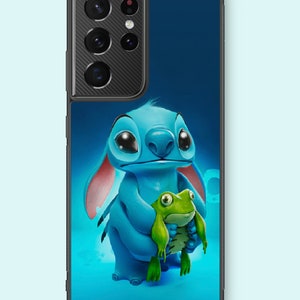 Peut inclure: Un personnage de dessin animé bleu et rose aux grands yeux tenant une grenouille verte. Le personnage est sur un fond bleu avec un étui de téléphone noir autour.