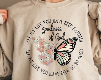 May include: A beige sweatshirt with a graphic design of a butterfly with flowers and the text "All my life you have been faithful, all my life you have been so good, goodness of God".