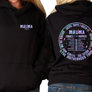 May include: Black hooded sweatshirt with a holographic design. The front of the sweatshirt says "Mama Tour" with a rock and roll hand gesture. The back of the sweatshirt says "Some days I rock it. Some days it rocks me. We're rockin' the motherhood tour. Mama makes it all happen." with a list of activities like laundry, kitchen, work, practice, playground, holidays, school, appointments, doctor visits, grocery store, and birthday parties.
