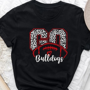 May include: Black t-shirt with a red and white leopard print design of the number 60 and a football with a red heart. The text "Bulldogs" is below the football.