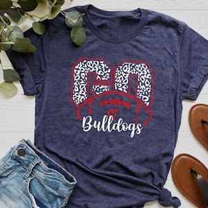 May include: A navy blue t-shirt with a white and red graphic of the number 20 in a leopard print design. The graphic also includes a football and the word "Bulldogs".
