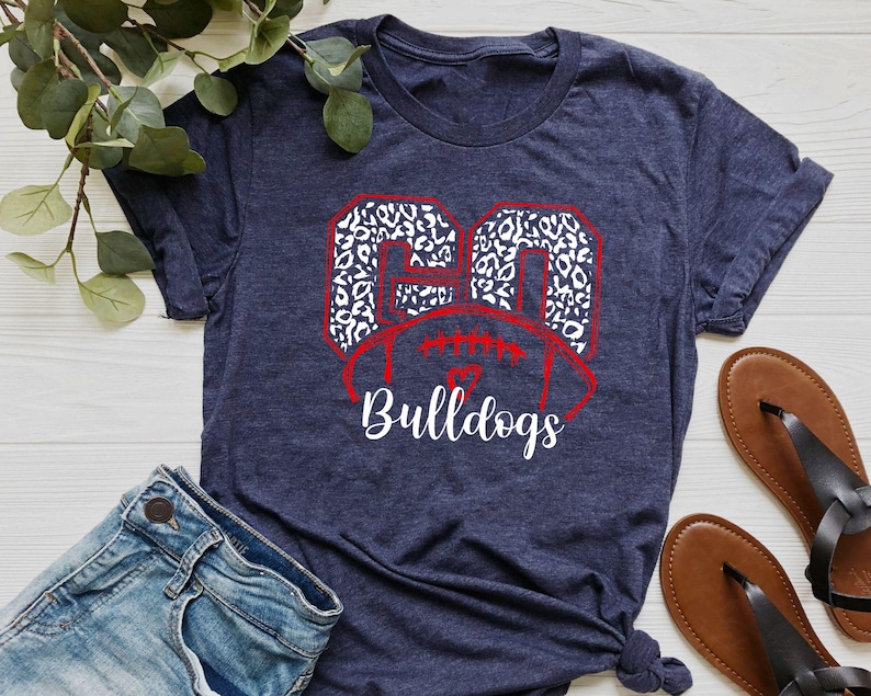 May include: A navy blue t-shirt with a white and red graphic of the number 20 in a leopard print design. The graphic also includes a football and the word "Bulldogs".