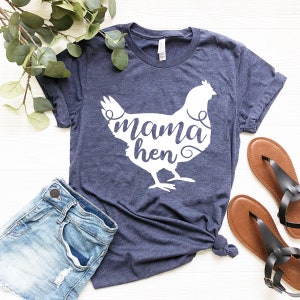 May include: A navy blue t-shirt with a white silhouette of a chicken and the text "mama hen" inside the silhouette.
