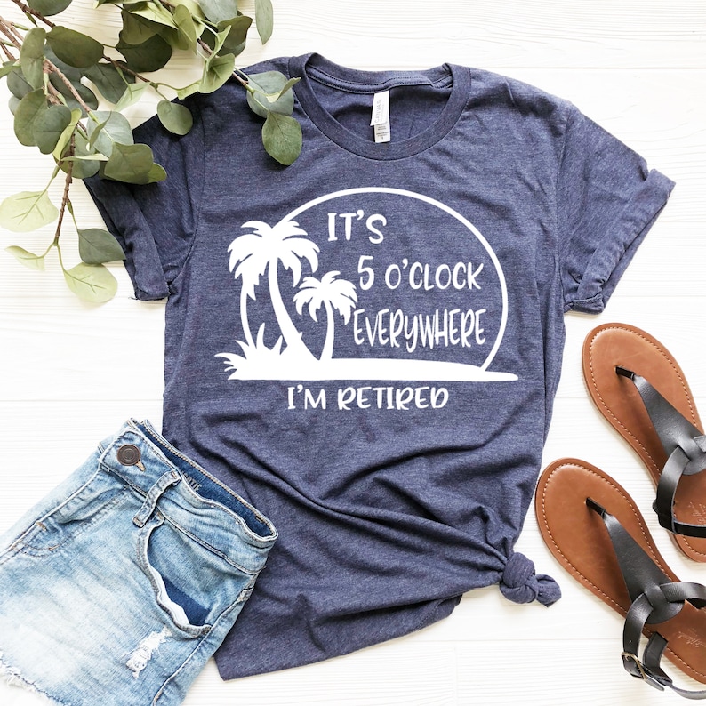 May include: A navy blue t-shirt with a white graphic of palm trees and the text "It's 5 o'clock everywhere I'm retired".