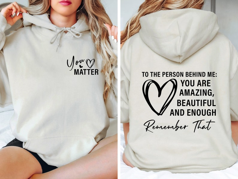 May include: A cream-colored hoodie with a black heart and the text "You Matter" on the front. The back of the hoodie has a black heart and the text "To the person behind me: You are amazing, beautiful and enough. Remember That."