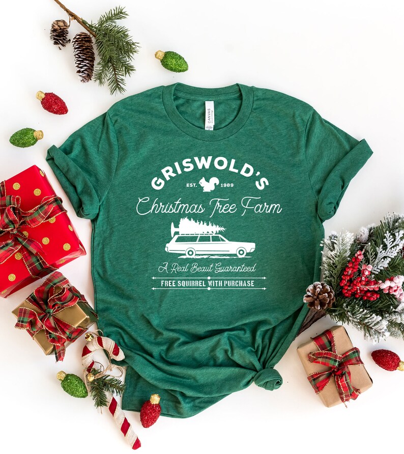May include: Green t-shirt with a white graphic design that says "Griswold's Christmas Tree Farm" with a squirrel, a Christmas tree, and a station wagon with a Christmas tree on top. The text also says "Est. 1989", "A Real Beaut Guaranteed", and "Free Squirrel With Purchase".