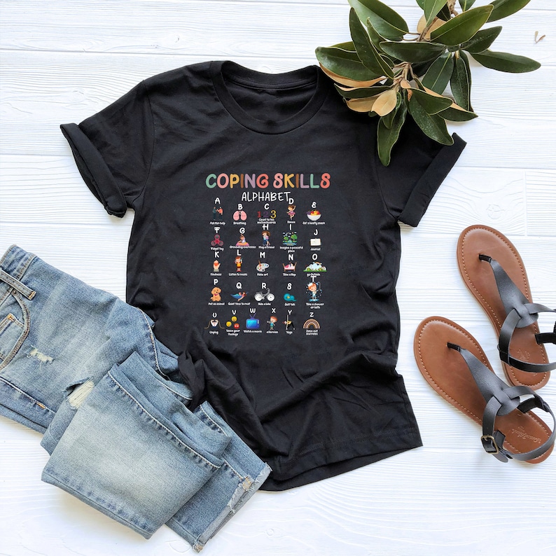 May include: Black t-shirt with a colorful graphic of the alphabet with coping skills for each letter. The graphic says "Coping Skills Alphabet".