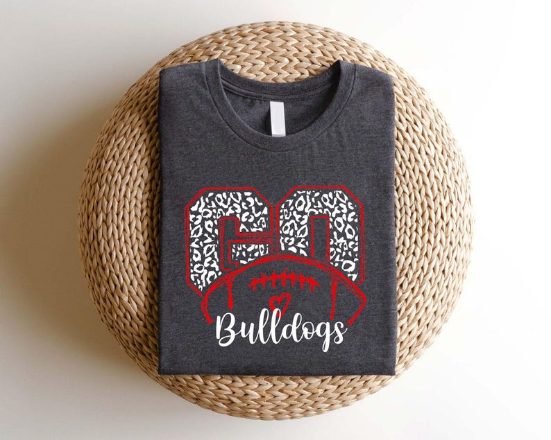 May include: A dark gray t-shirt with a white and black leopard print football design and the text "Bulldogs" in red.