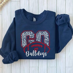 May include: Navy blue sweatshirt with a white and black leopard print football design and the text "Bulldogs".