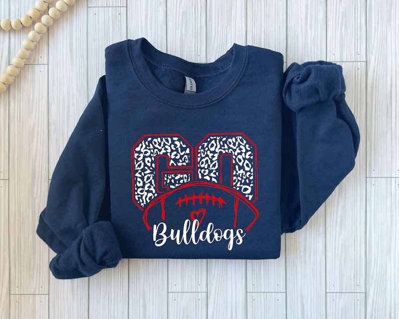 May include: Navy blue sweatshirt with a white and black leopard print football design and the text "Bulldogs".