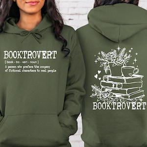 May include: A green hooded sweatshirt with the text "BOOKTROVERT [book - tro - vert - noun] A person who prefers the company of fictional characters to real people" on the front and a stack of books with a cup of coffee and flowers on the back.