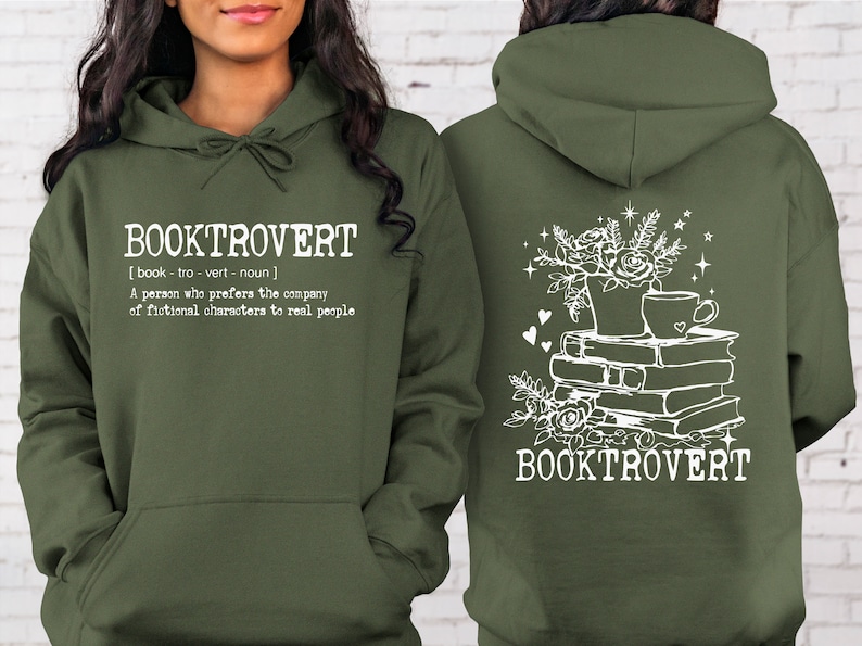 May include: A green hooded sweatshirt with the text "BOOKTROVERT [book - tro - vert - noun] A person who prefers the company of fictional characters to real people" on the front and a stack of books with a cup of coffee and flowers on the back.