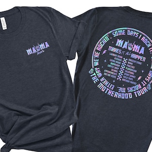 May include: A dark blue t-shirt with a holographic design. The front of the shirt says "Mama Tour" and the back says "Some days I rock it. Some days it rocks me. We're rockin' the motherhood tour. Mama makes it all happen." The design includes a list of activities like laundry, kitchen, grocery store, work, practice, playground, vacations, school, doctor visits, and birthday parties.