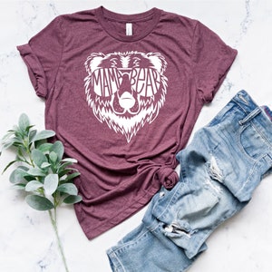 May include: A maroon t-shirt with a white bear graphic. The bear is wearing sunglasses and the text "Mama Bear" is inside the sunglasses.