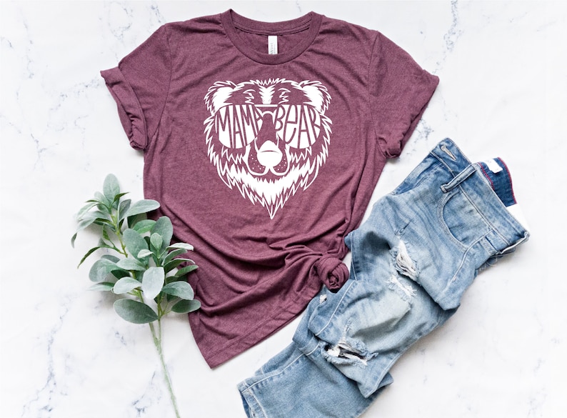 May include: A maroon t-shirt with a white bear graphic. The bear is wearing sunglasses and the text "Mama Bear" is inside the sunglasses.