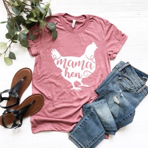 May include: A pink t-shirt with a white silhouette of a chicken and the text "mama hen" on the front.