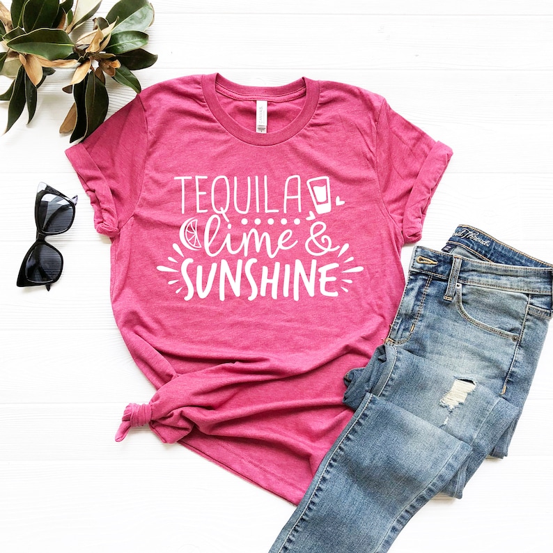 May include: Pink t-shirt with white text that reads "Tequila, lime & sunshine" with a small image of a shot glass and a lime wedge.