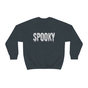 May include: Dark gray sweatshirt with the word "SPOOKY" in white, dripping font. The sweatshirt is a crew neck style, perfect for Halloween or spooky season. The text is centered on the chest.