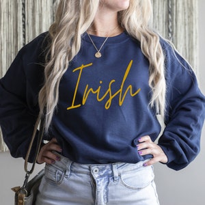 May include: A navy blue sweatshirt with the word "Irish" written in gold script on the front.