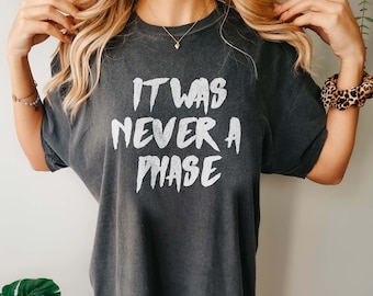 May include: A dark gray oversized t-shirt with the text "It was never a phase" printed in white.