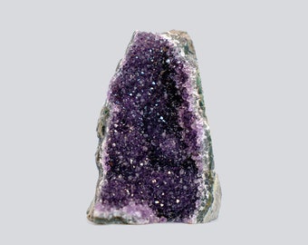 May include: A natural amethyst geode, showcasing a deep purple crystal interior. The geode's rough, gray exterior contrasts with the sparkling, crystalline structure within. The amethyst crystals are densely packed, creating a visually striking display.