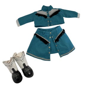 May include: A turquoise denim jacket and skirt set with black fringe and silver buttons. The set is paired with white and black cowboy boots with decorative stitching. A western-themed outfit.