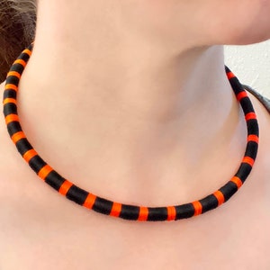 May include: A black and orange striped ribbon choker necklace.
