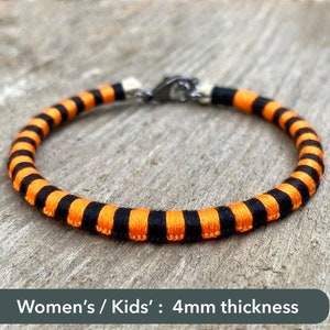 Peut inclure: Bracelet ray&eacute; noir et orange avec un fermoir argent&eacute;. Femmes / Enfants : 4 mm d'&eacute;paisseur.